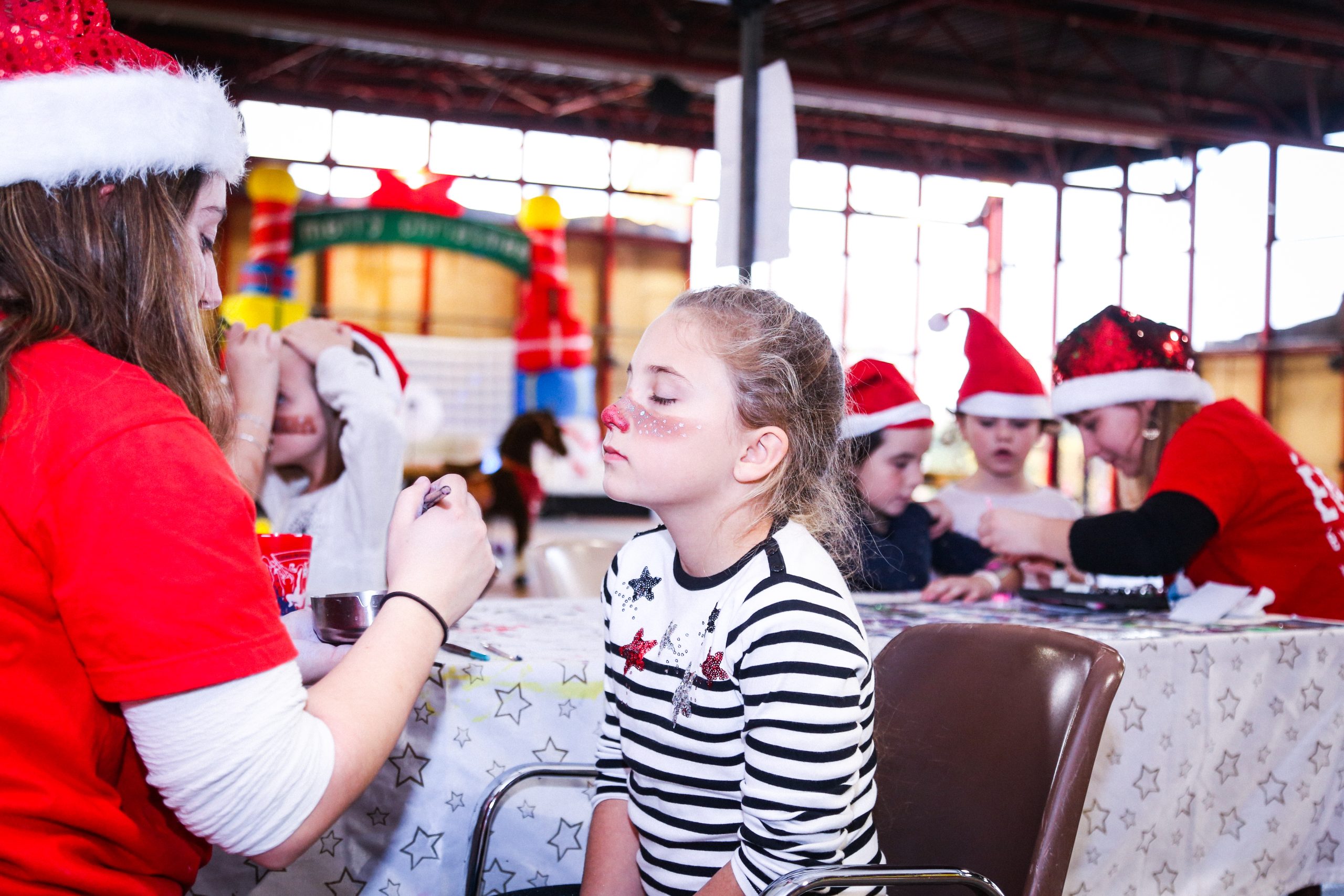 enfant qui se fait maquiller pendant un arbre de noel